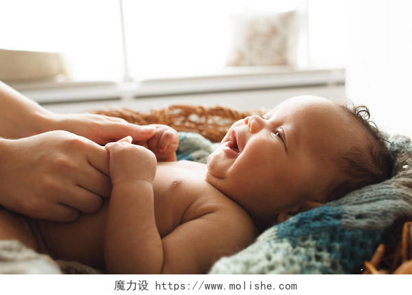 可爱的新生婴儿抬头看着妈妈和她手牵手